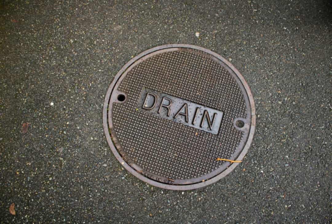 Round metal cover marked DRAIN set in pavement