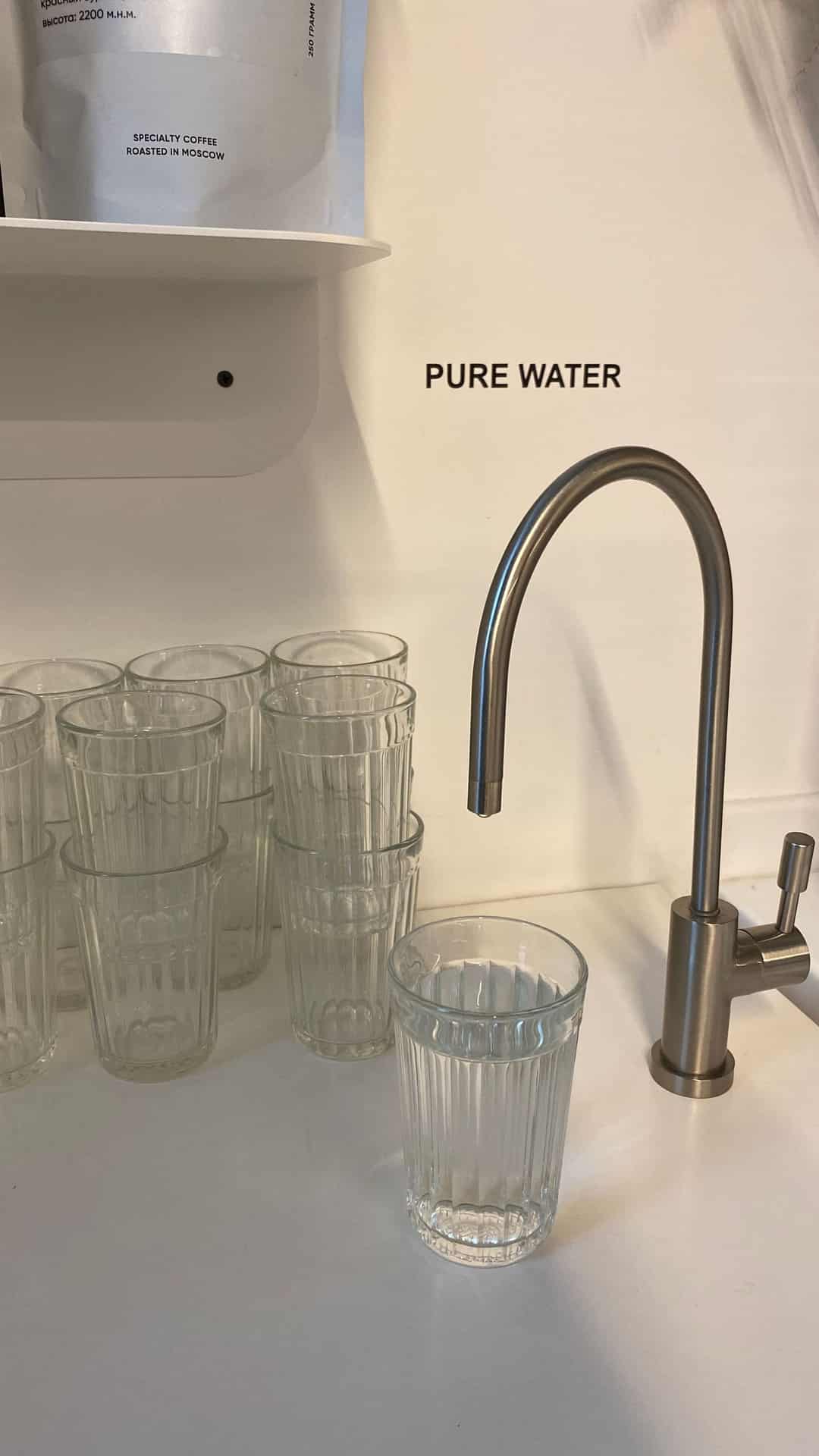 Kitchen faucet beside a row of drinking glasses