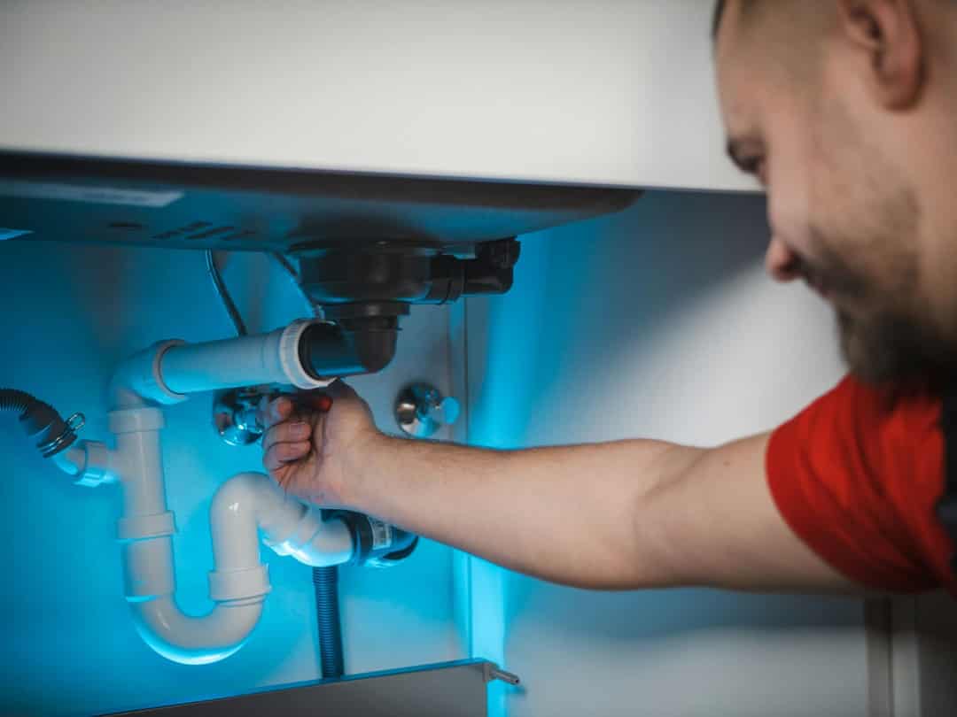 Plumber fitting a drain trap under a sink
