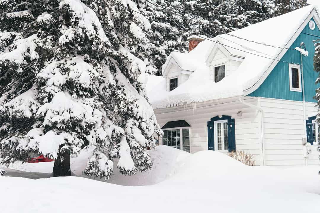 House surrounded by deep snow and trees