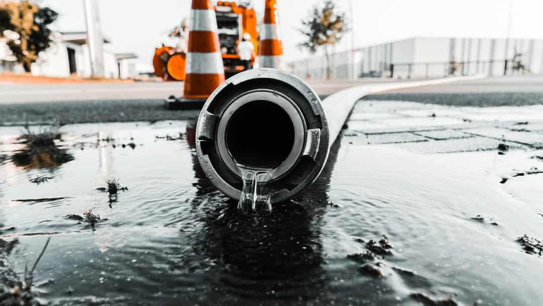 Water pouring from a large pipe at a street work site