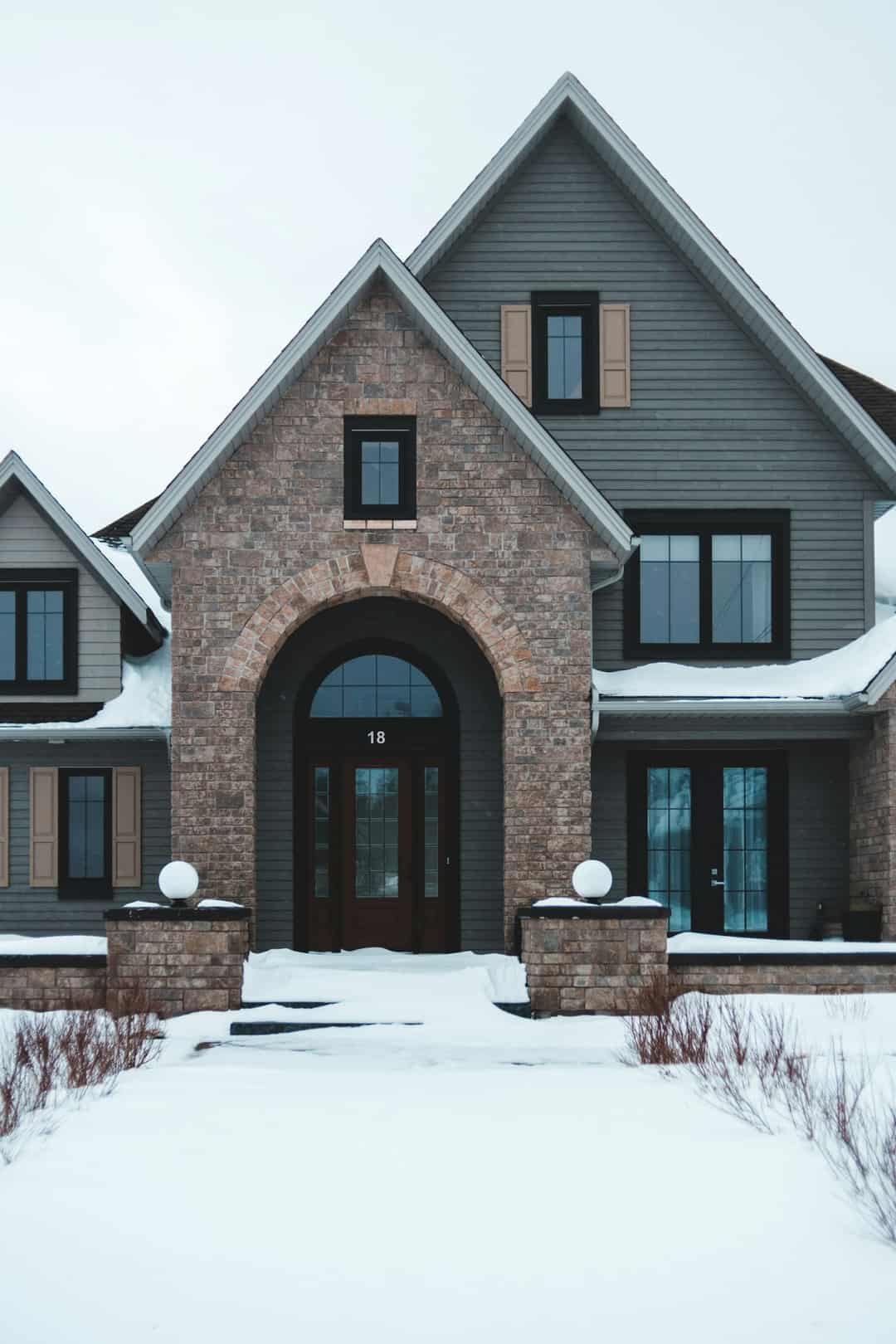 Brick house with snow on the roof and lawn