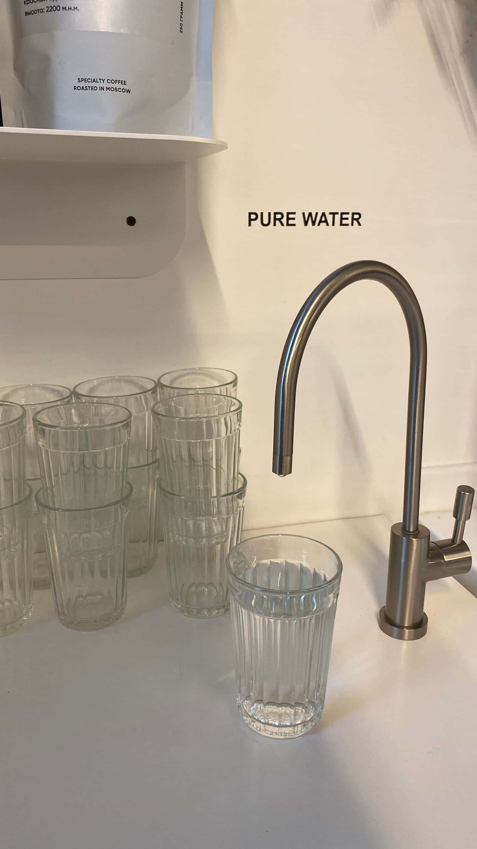 Kitchen faucet beside a row of drinking glasses