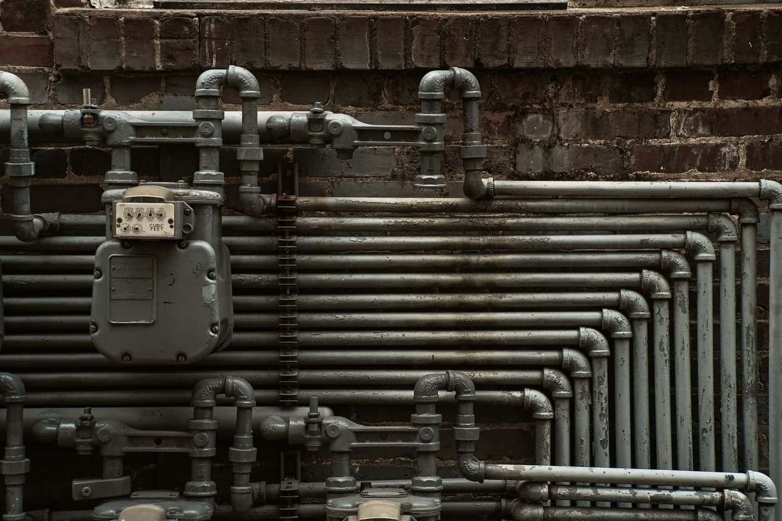 Steel gas piping and a gas meter on a brick wall