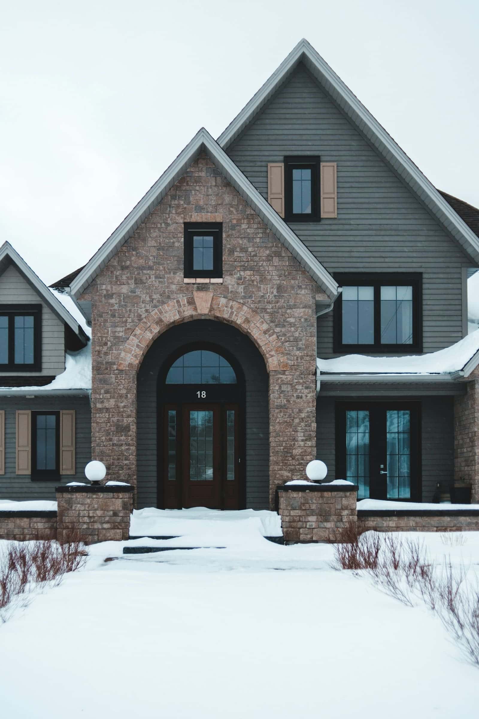 Brick house with snow on the roof and lawn