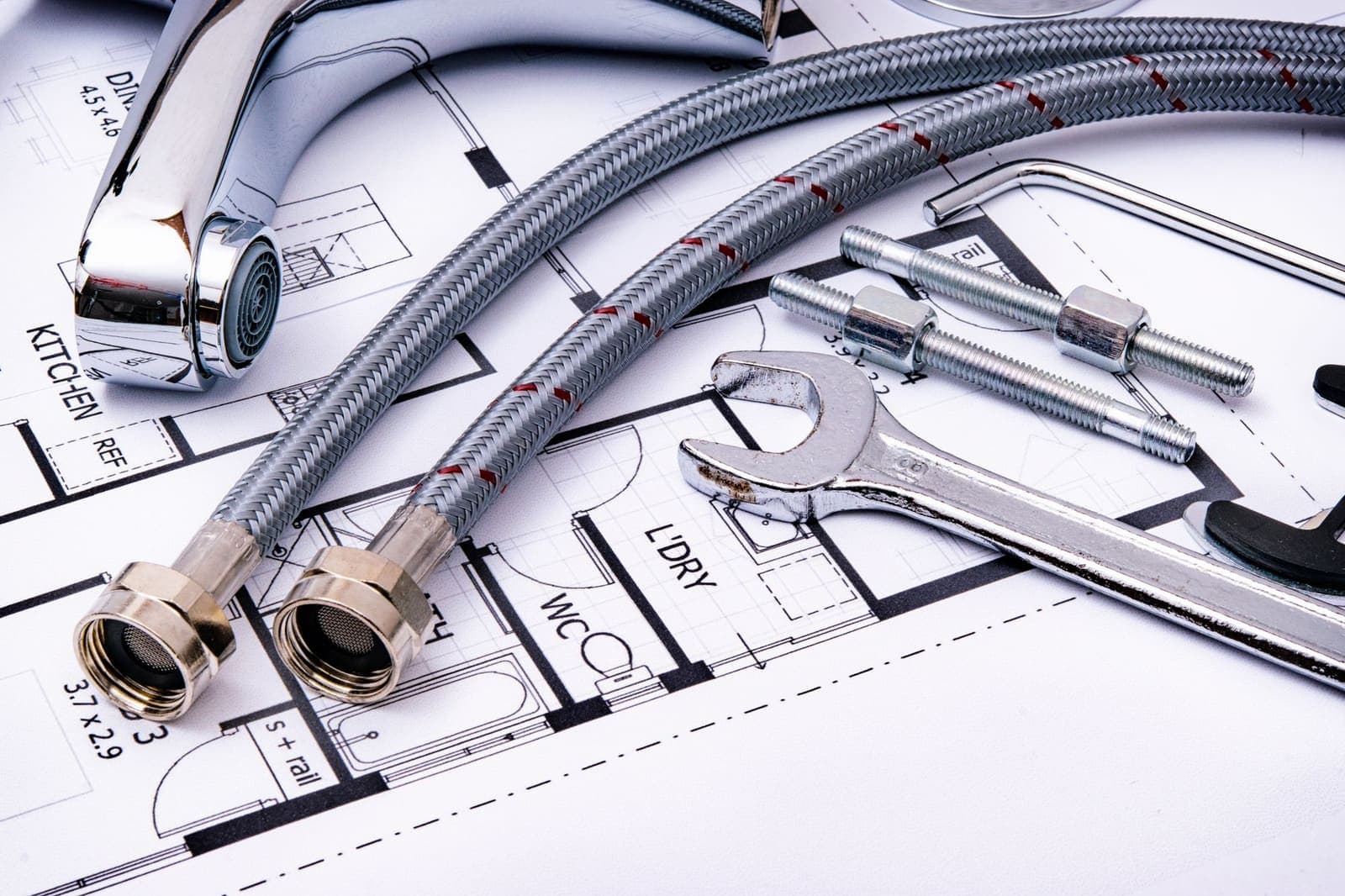 Braided supply hoses, a faucet and a wrench on a plumbing plan