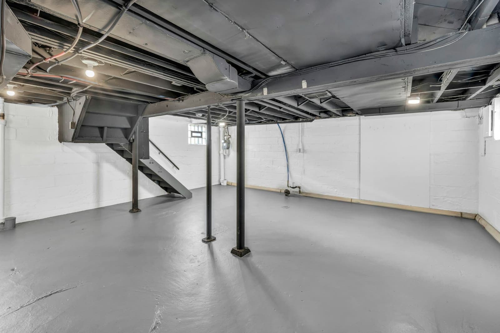 Unfinished basement with exposed joists and support posts