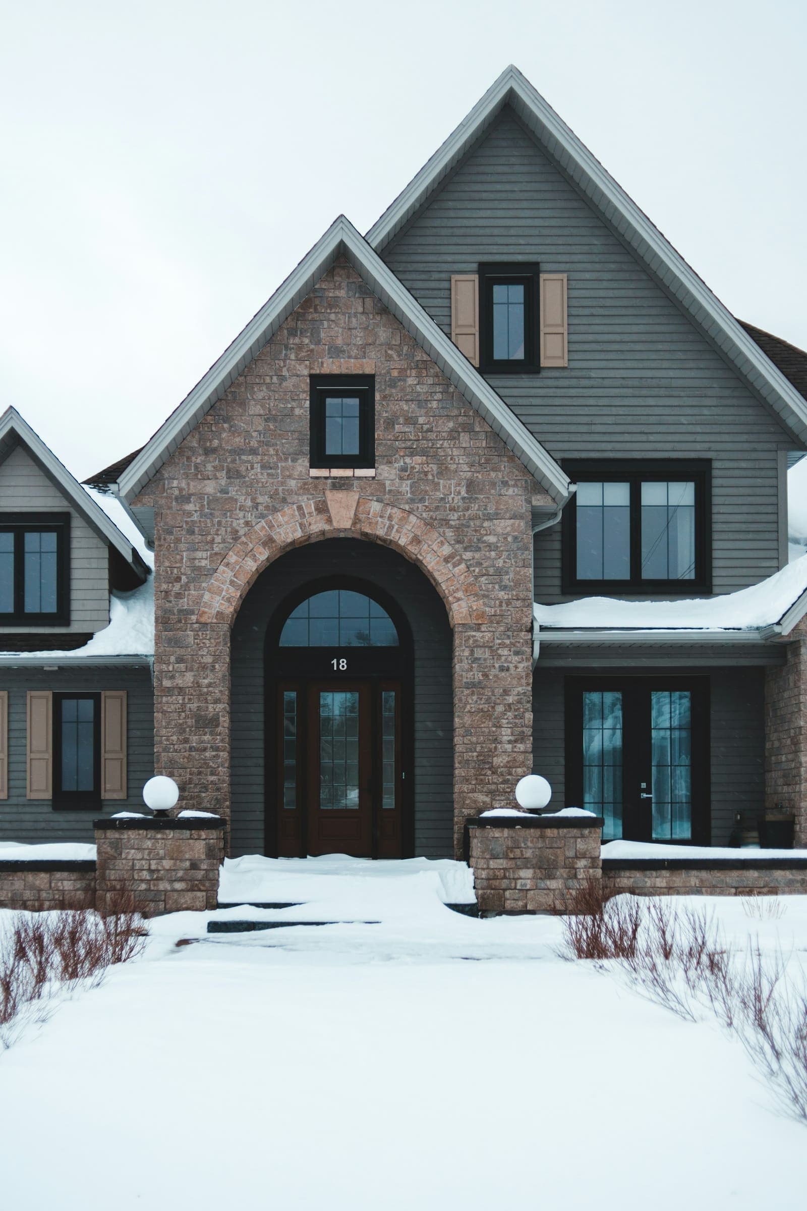 Brick house with snow on the roof and lawn