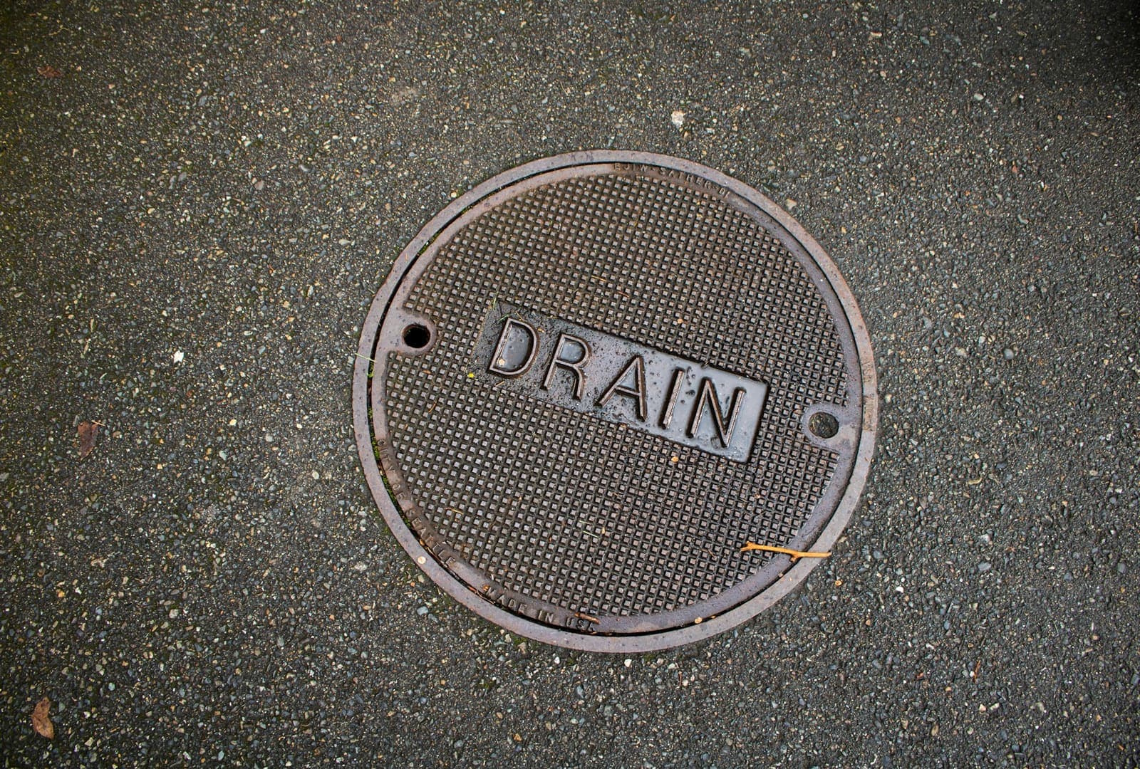 Round metal cover marked DRAIN set in pavement