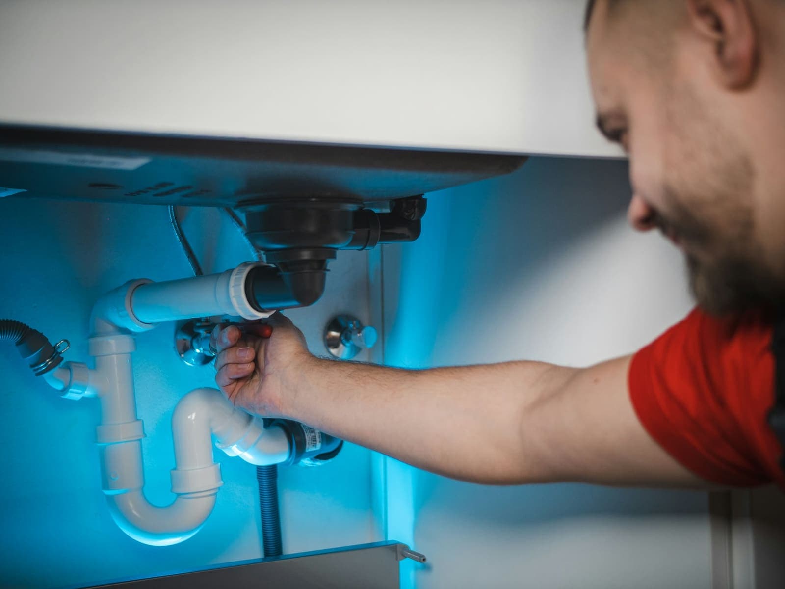 Plumber fitting a drain trap under a sink