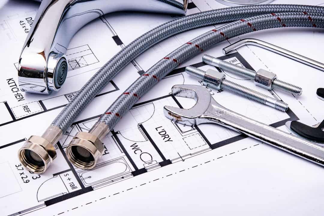 Braided supply hoses, a faucet and a wrench on a plumbing plan