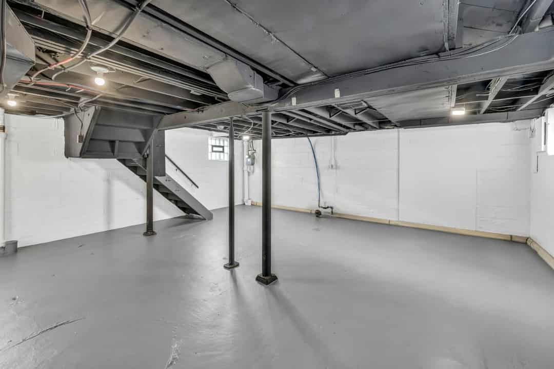 Unfinished basement with exposed joists and support posts